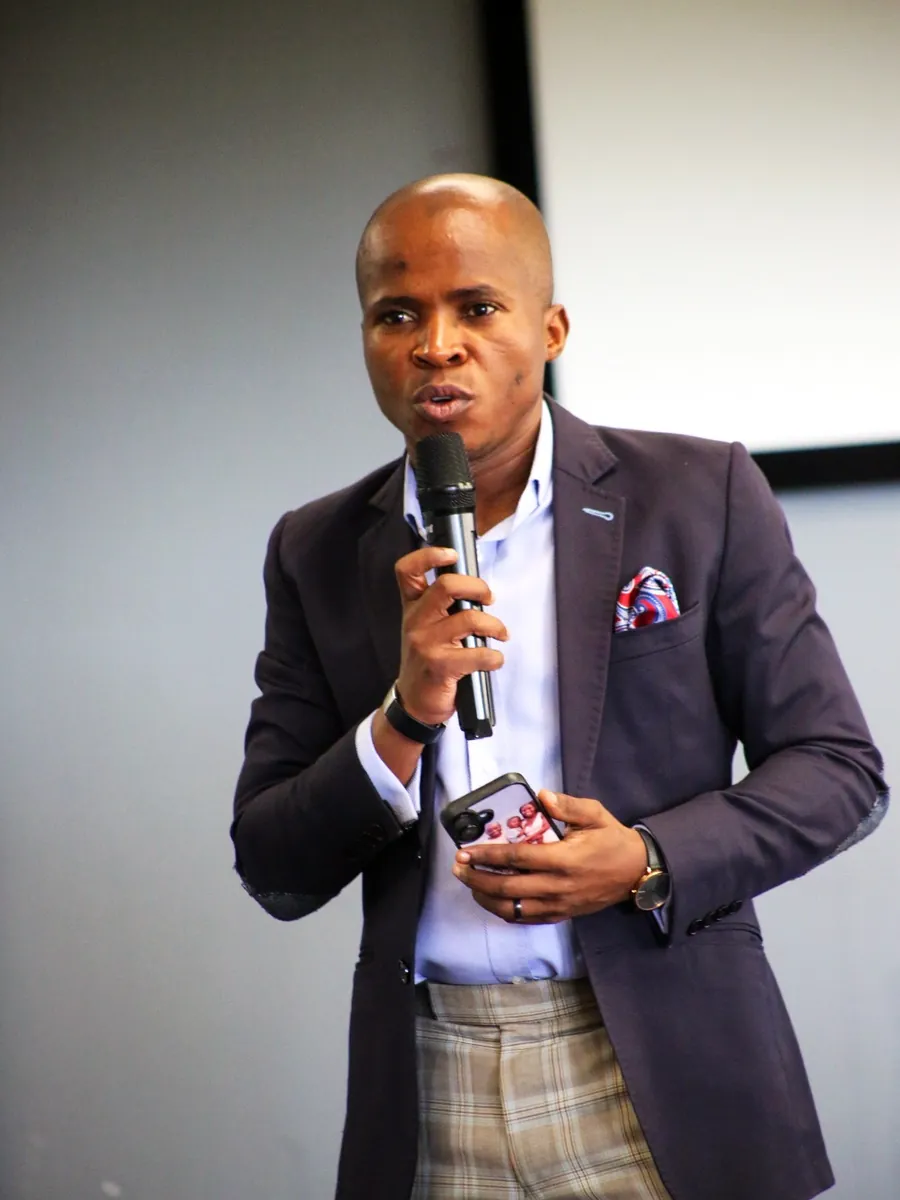 Speaking to a room of delegates with a handheld microphone